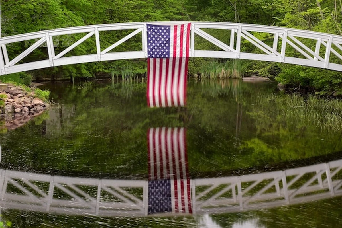 Most pieszy w Somesville Mount Desert Island z flagą USA odbijającą się w stawie