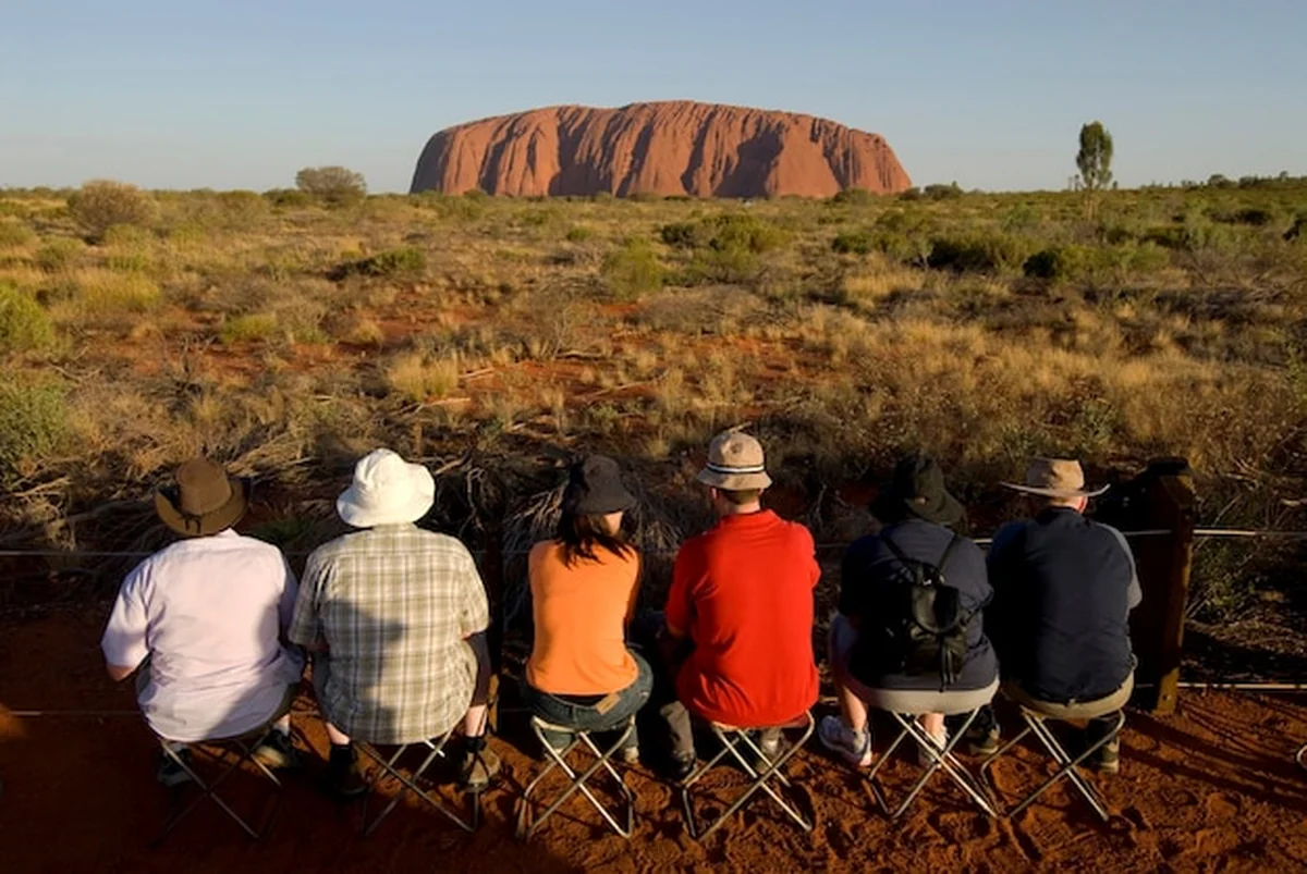 Aborygeńska skała Uluru z turystami w Yulara oczekującymi na zachód słońca
