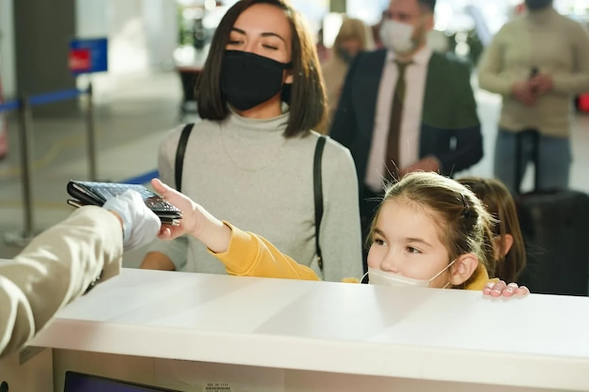 Mała dziewczynka w masce i mama na lotnisku przed rejestracją