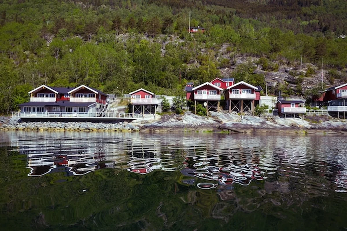 Tradycyjny norweski czerwony drewniany dom nad jeziorem i górami w oddali