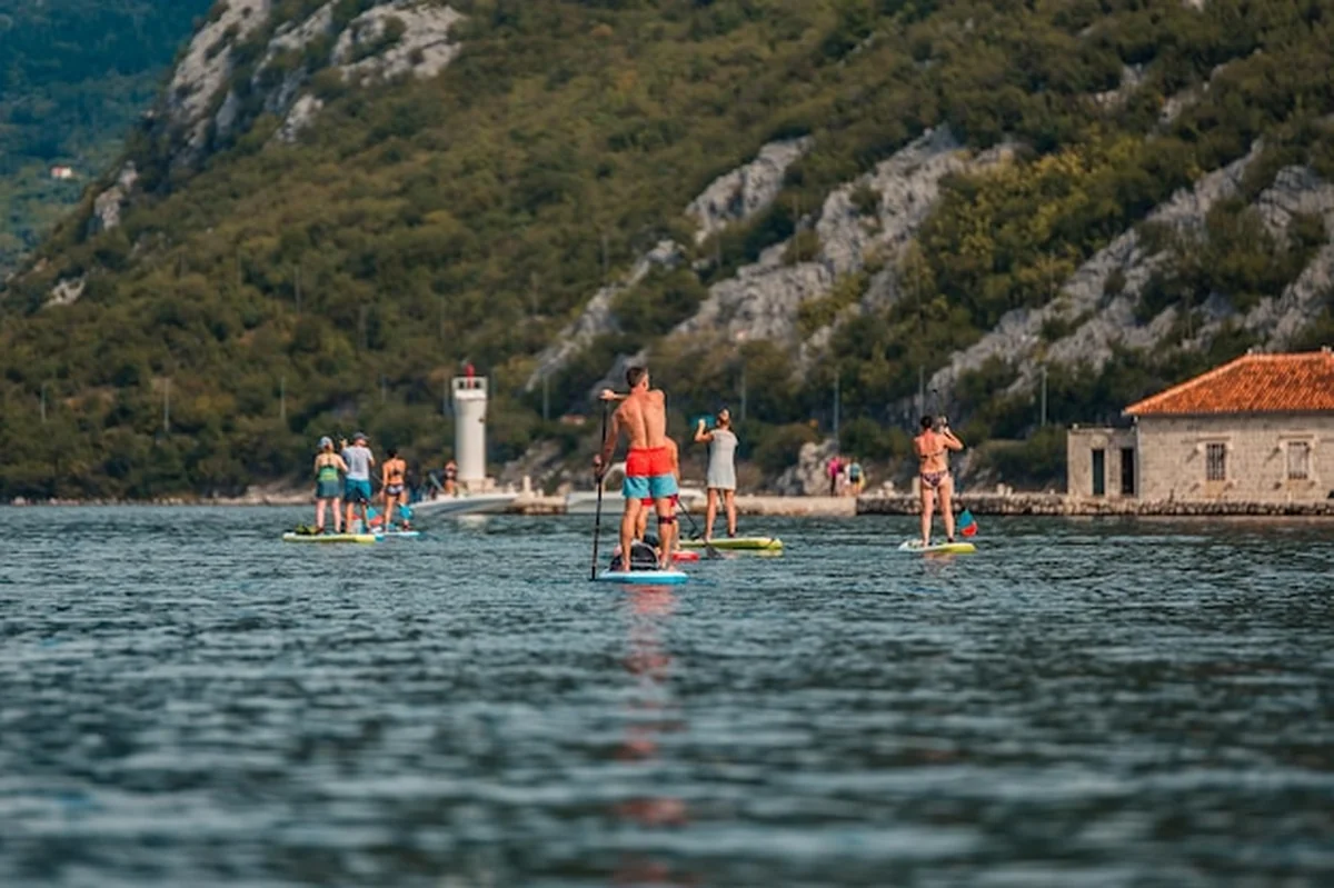 Mężczyzna na paddleboardzie na spokojnym morzu z górskim krajobrazem