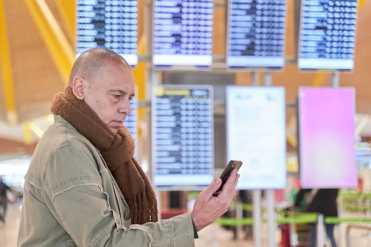 Mężczyzna spoglądający na telefon z informacjami o locie